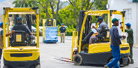Workers operating forklifts outside while other workers walk around them