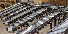 Rows of gravity conveyors lined up on a warehouse floor in front of pallets