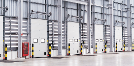 Row of industrial warehouse dock doors with loading equipment and safety barriers inside a distribution center.