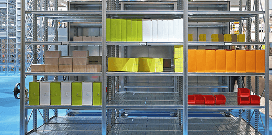 A rows of heavy-duty shelving units holding various colorful storage supplies and packages in a warehouse