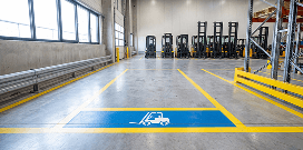 Blue floor safety zone with yellow striping in a warehouse.